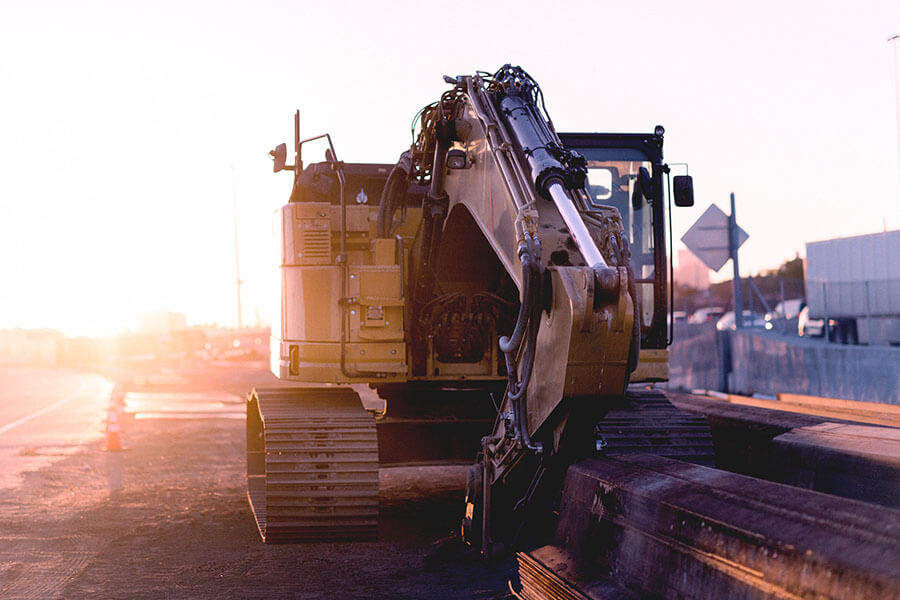 A yellow excavator on the side of the road.