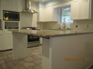 A kitchen with white cabinets and granite counter tops.