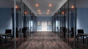 An office with glass walls and wooden floors.