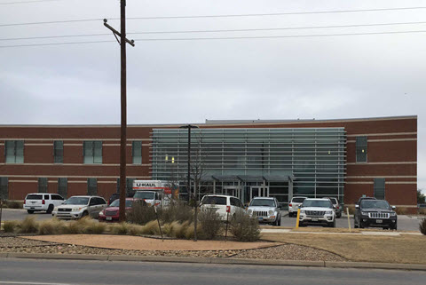 A large brick building with cars parked in front of it.