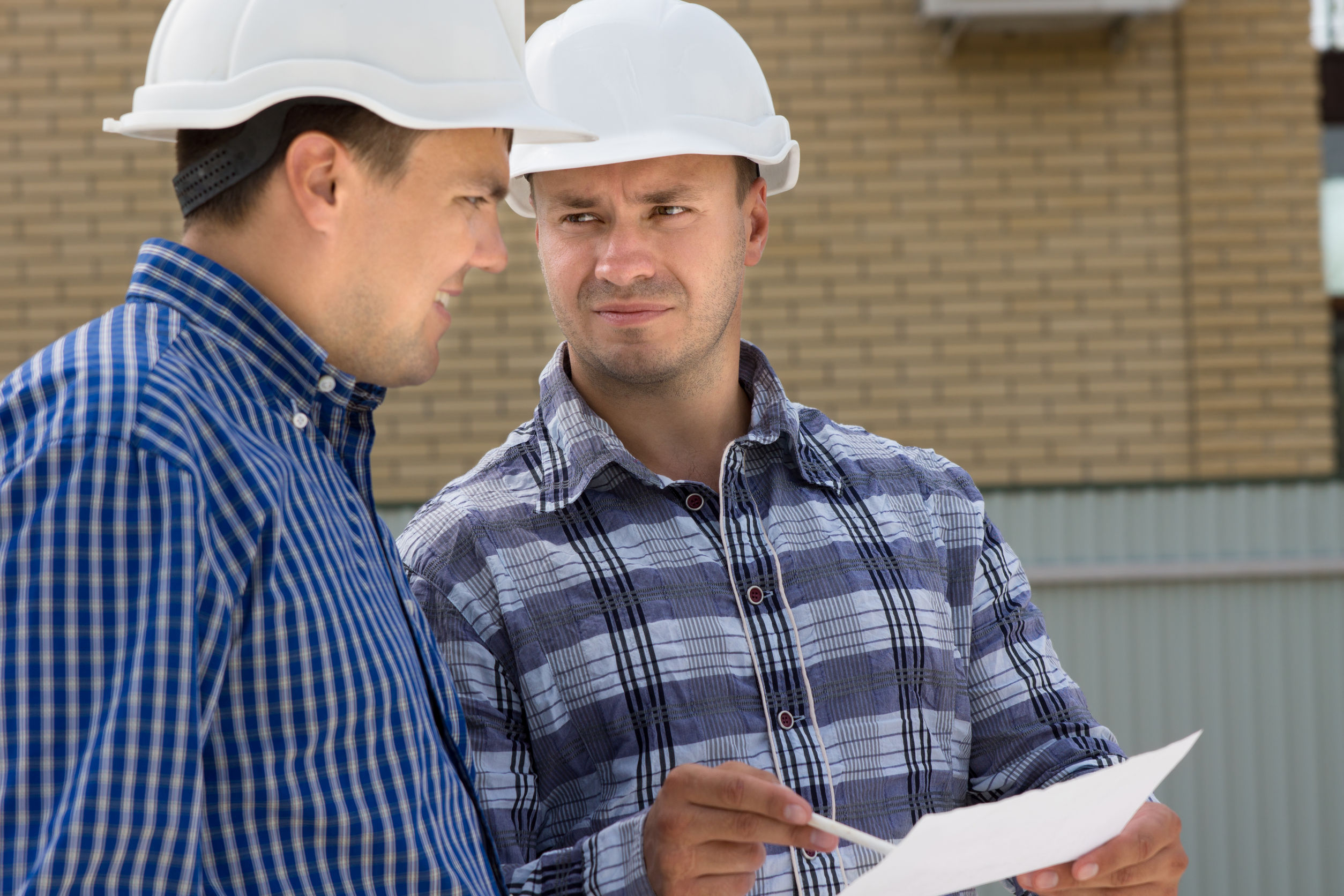 Two men in hard hats talking to each other.