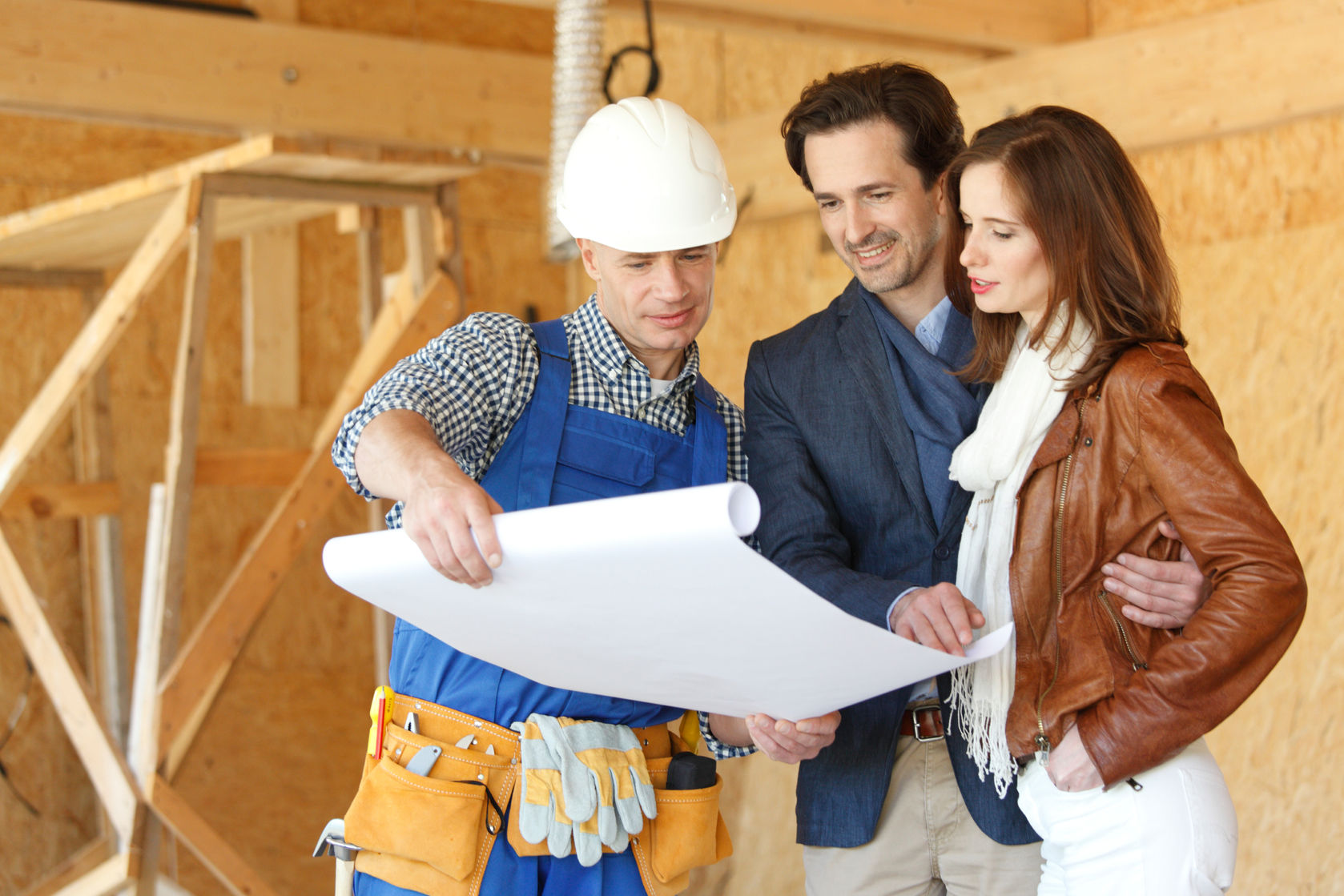 A man and woman are looking at blueprints in a house.