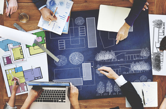 A group of people working with blueprints on a table.