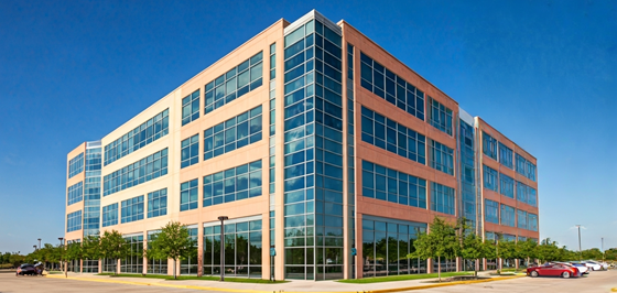 A modern four-story office building with large glass windows, surrounded by trees and a parking lot under a clear blue sky. A modern four-story office building with large glass windows, surrounded by trees and a parking lot under a clear blue sky.