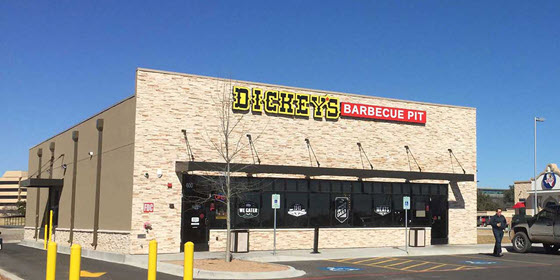 Exterior view of a Dickey's Barbecue Pit restaurant with a beige brick facade, large windows, and a parking lot in front. Exterior view of a Dickey's Barbecue Pit restaurant with a beige brick facade, large windows, and a parking lot in front.